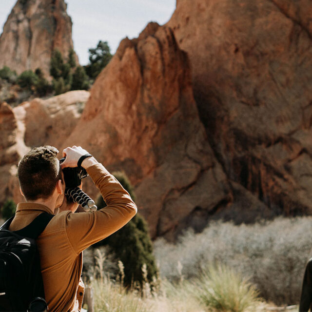 Back shot of a man taking a photo of the red rocks