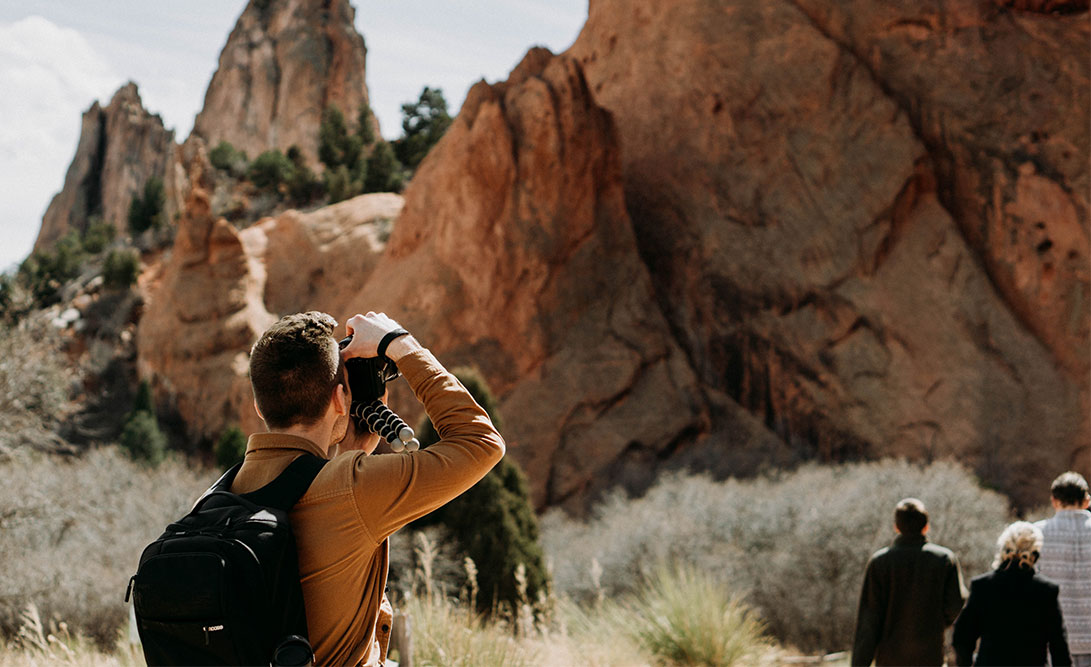 Back shot of a man taking a photo of the red rocks