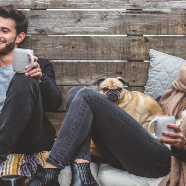A man and woman sitting while holding their coffee mugs