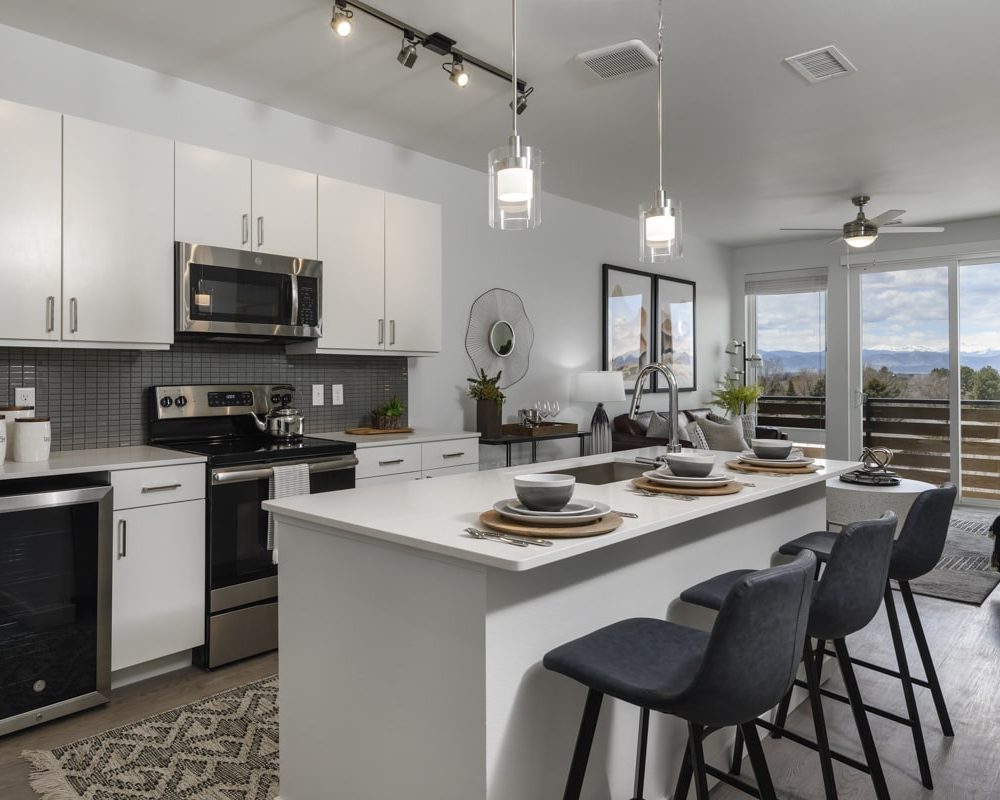 Three-Bedroom Apartments in Denver, CO - Deco - Kitchen with Granite Style Island, Stainless-Steel Appliances, and Modern Lights